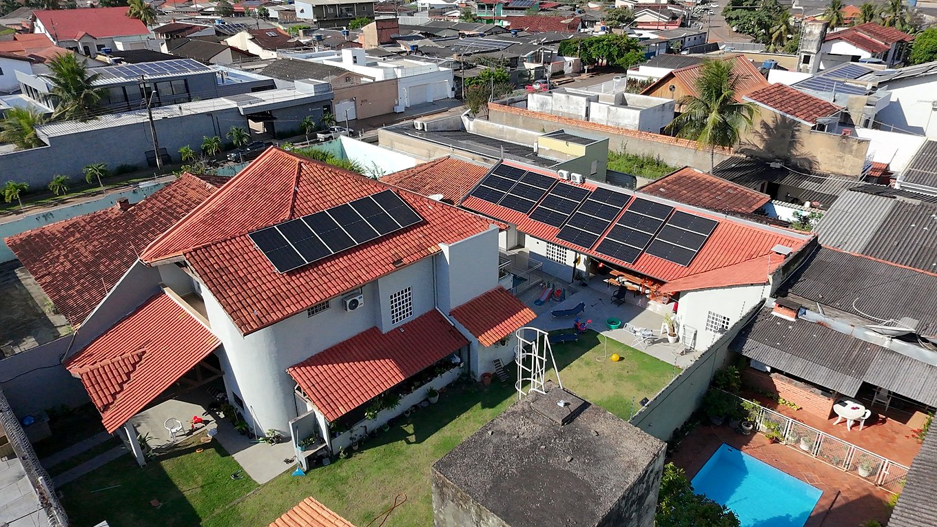 Vista aérea de residência ampla com dois conjuntos de módulos solares no telhado